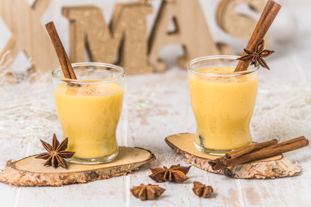 Two glasses of eggnog with cinnamon sticks on white wooden background, christmas. Auld Man's milk, Coquito or Creme de Vie or Eggnog.の写真素材