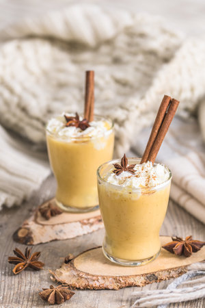 Two glasses of eggnog with whipped cream and cinnamon. Auld Man's milk, Coquito or Creme de Vie or Eggnog. vertical.の写真素材