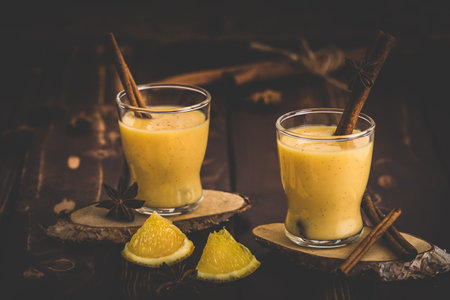 Two glasses of eggnog with cinnamon sticks on dark wooden background. Auld Man's milk, Coquito or Creme de Vie or Eggnog.の写真素材