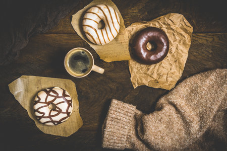 Chocolate donuts and coffee on a dark wooden table, cozy scene of a coffee break, top viewの写真素材