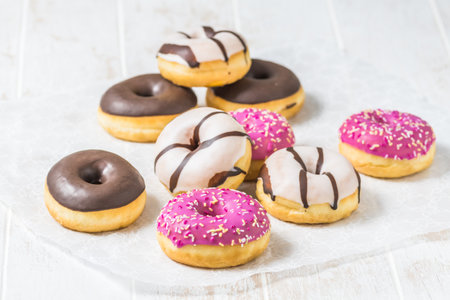 Colorful Donuts, Berliner, Krapfen with sugar icing and chocolate on white wooden background, vertical with copy spaceの写真素材