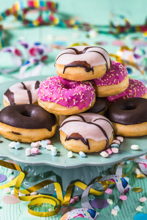 Donuts, donuts, donuts with streamers and confetti. Colorful picture of carnival, birthday and fasching, green background, verticalの写真素材