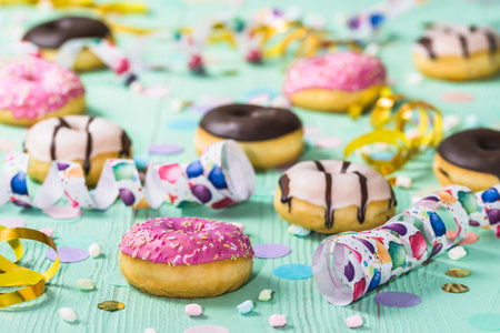 Donuts, donuts, donuts with streamers and confetti. Colorful picture of carnival, birthday and fasching, green backgroundの写真素材