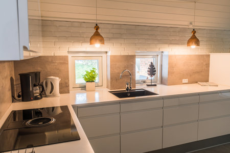 Modern kitchenette with white worktop, black sink and coppery metal lamps in industrial styleの写真素材