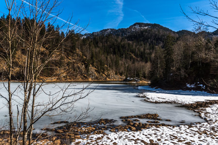 Alpine landscape with a frozen lake at the end of winter, partly covered with snowの写真素材