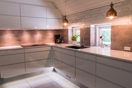 Modern kitchenette with white worktop, black sink and coppery metal lamps, industrial styleの写真素材