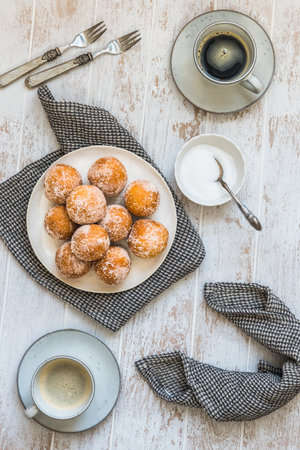 Fried curd balls with sugar and two cups of coffee on white wooden background, top view. Concept of coffee break.の写真素材
