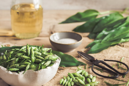 Wild garlic buds and leaves, salt and vinegar on a rustic wooden background. Preparation for canning.の写真素材