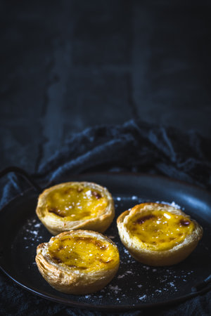 Traditional portuguese dessert, pastel de nata, pasteis de nata, egg tart, on black background, vertical with copy spaceの写真素材