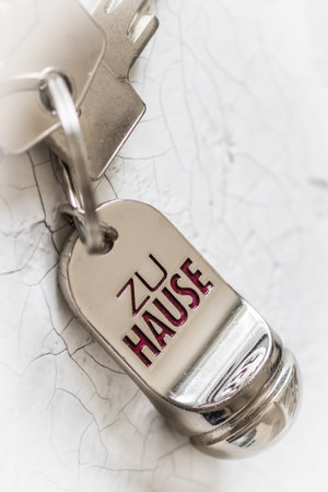 Key ring with two keys and tag with German text At Home (translation: at home) on a white background, vertical with copy spaceの写真素材