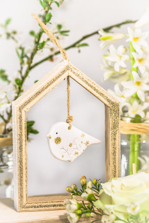Floral spring decoration with white rose, cherry branches, hyacinth and wooden bird, verticalの写真素材