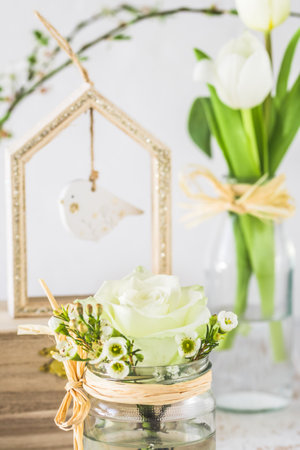 Floral spring decoration with white rose, cherry branches, hyacinth and wooden bird, verticalの写真素材