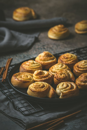 Cinnamon rolls on a black table on dark background, verticalの写真素材