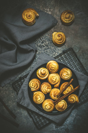 Cinnamon rolls on a black table on dark background, top viewの写真素材