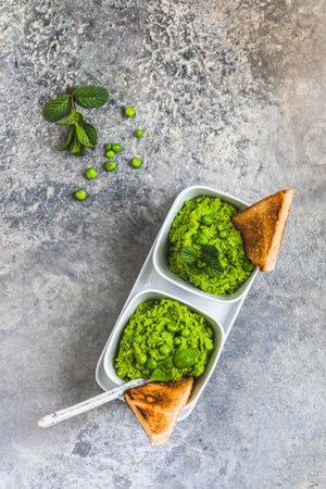 Pea puree with basil and roasted bread on rustic gray background, top view, copy spaceの写真素材
