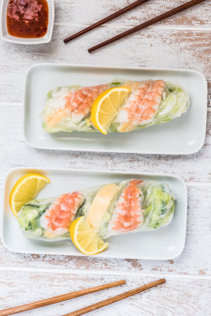 Two summer rolls with salad and prawns on a white wooden background, japanese, asian food. Top view.の写真素材