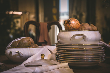 Stacked plates with gold rim and bowl with onions on an old wooden tableの写真素材