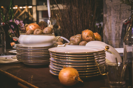 Stacked plates with gold rim and bowl with onions on an old wooden tableの写真素材