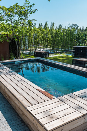 Modern swimming pool with wooden surround in a gardenの写真素材
