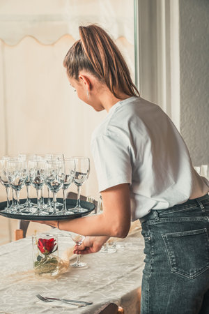 Young waitress sets tables in the restaurant with glasses, verticalの写真素材