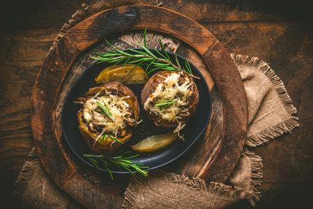 Two baked potatoes with mushrooms, sour cream and cheese on a rustic wooden background, top view,の写真素材