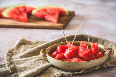 Pieces of watermelon as finger food on a plate, sliced watermelon in the backgroundの写真素材