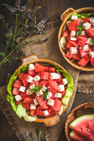 Fresh watermelon salad with feta cheese and mint on rustic wooden background, top viewの写真素材