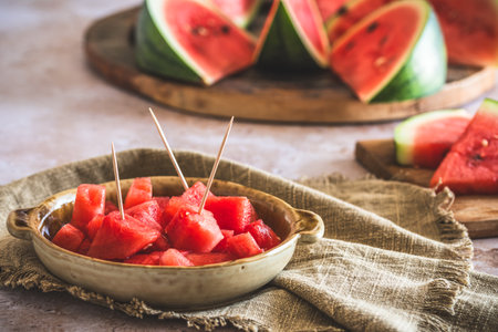 Pieces of watermelon as finger food on a plate, sliced watermelon in the backgroundの写真素材