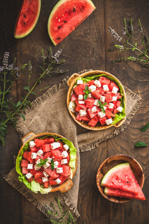 Fresh watermelon salad with feta cheese and mint on rustic wooden background, top viewの写真素材