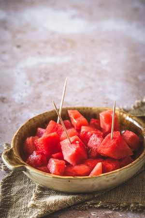 Pieces of watermelon as finger food on a plate on beige background, vertical with copy spaceの写真素材