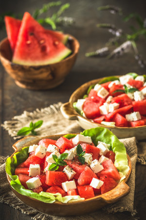 Fresh watermelon salad with feta cheese and mint on rustic wooden background, verticalの写真素材