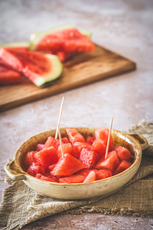 Pieces of watermelon as finger food on a plate, sliced watermelon in the background, verticalの写真素材