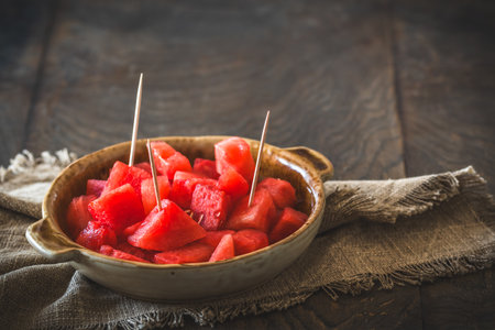 Pieces of watermelon in a bowl on a rustic wooden background, with copy spaceの写真素材