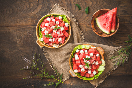 Fresh watermelon salad with feta cheese and mint on rustic wooden background, top view with copy spaceの写真素材