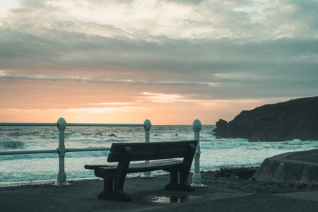 Bench with view of the beach on the north Cornish coast near Bude, England after sunset, copy space