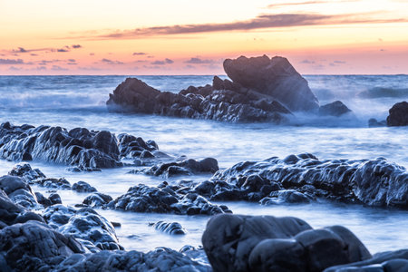 Rocky shore of a coast in the sunset, blurred water from long time exposure