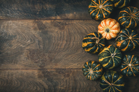 Various small pumpkins with a striped pattern on wooden background, top view with copy spaceの写真素材