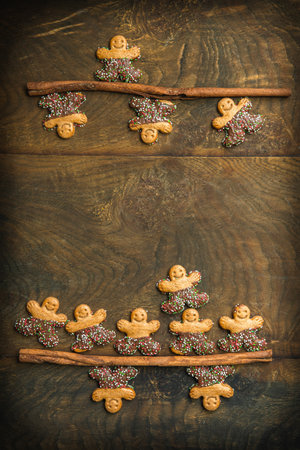 Sweet cookie characters with chocolate on cinnamon sticks on a dark wooden background, vertical with copy spaceの写真素材