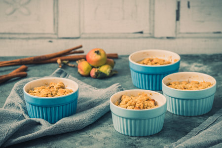 Apple crumble in small blue molds on a rustic gray tableの写真素材