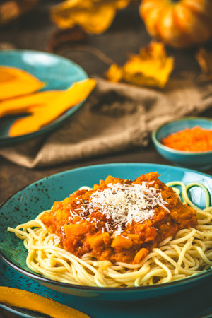 Spaghetti with homemade vegan Bolognese sauce made from red lentils and pumpkin on wooden background, turquoise earthenware, verticalの写真素材