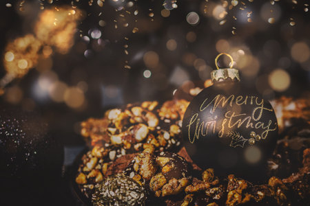 Cookies, gingerbread and Christmas decoration, black and gold, black bauble with text Merry...