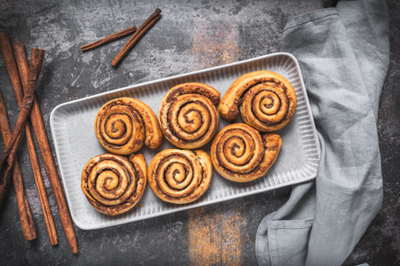 Homemade cinnamon rolls on a gray earthenware tray on gray background, top viewの写真素材