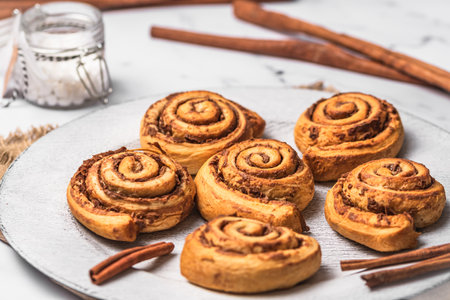 Homemade cinnamon rolls on white plate on white marble backgroundの写真素材