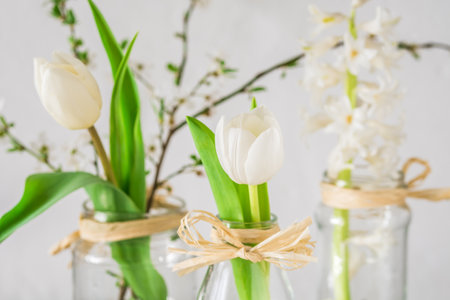 Spring flowers in glasses on white backgroundの写真素材