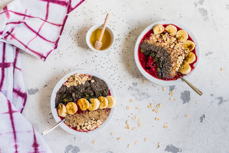 Healthy breakfast. Smoothie bowls with blueberries, banana, oat flakes, chia seeds, quinoa, pumpkin seeds and honey. Top view.の写真素材