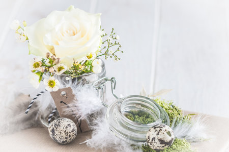 White rose in preserving jar, decorated with spring flowers, spring or easter decorationの写真素材