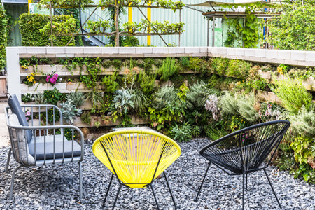 Garden chairs in a sitting area with vertical flower bedsの写真素材