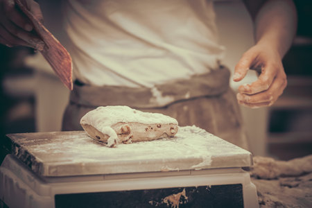 A female baker weighs pieces of dough. Traditional crafts.の写真素材
