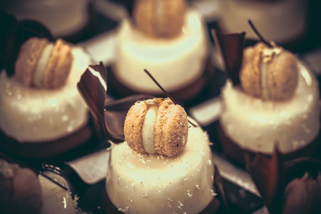 Tartlet with creamy glaze, decorated with a macaroon, coconut flakes and chocolate, close-upの写真素材