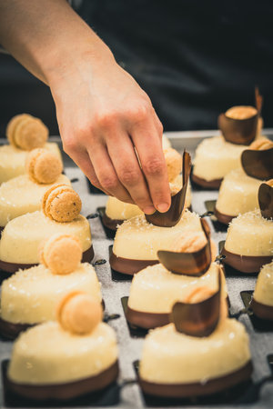 Confectioner's hand decorating tartlets with chocolate. Preparation of the tartlets by a professional pastry chef.の写真素材
